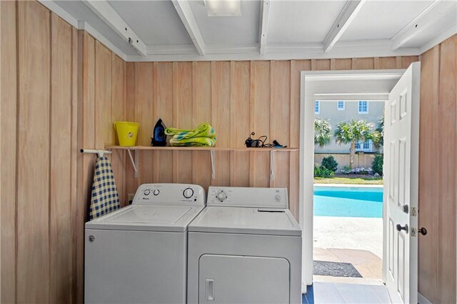 clothes washing area with wood walls and washer and dryer