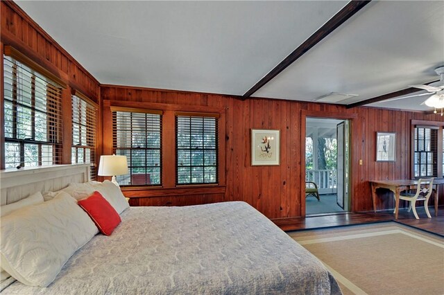 bedroom featuring wood walls, ceiling fan, beam ceiling, and multiple windows