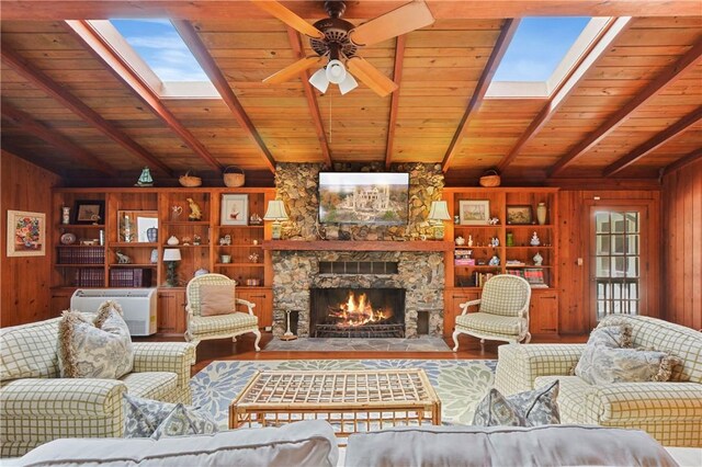 living room with ceiling fan, wooden walls, wooden ceiling, hardwood / wood-style floors, and a stone fireplace