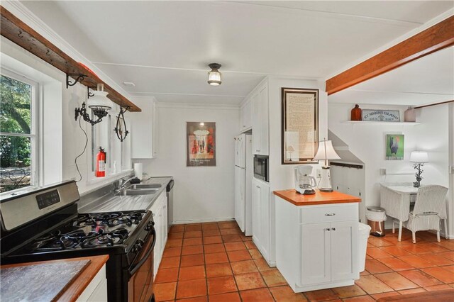 kitchen with sink, black gas range, white fridge, white cabinetry, and light tile patterned flooring