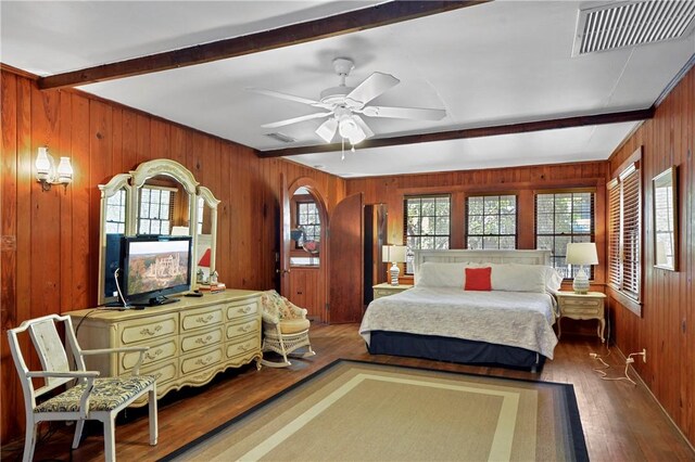 bedroom with hardwood / wood-style floors, ceiling fan, beam ceiling, and wooden walls