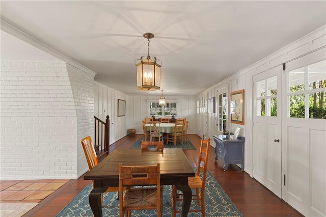 dining area featuring crown molding, brick wall, and dark hardwood / wood-style floors