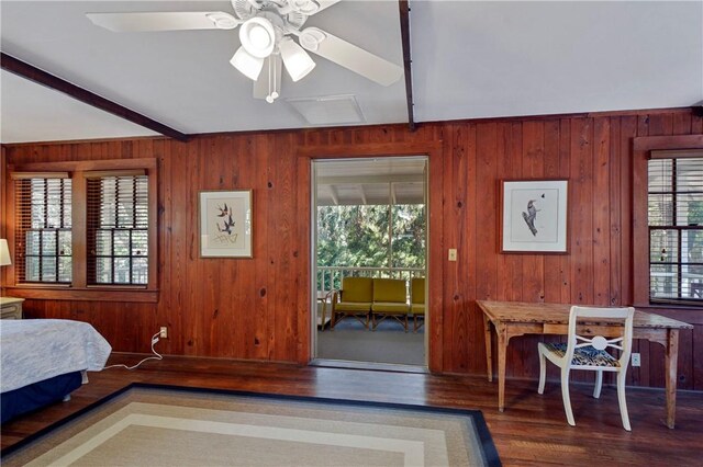 bedroom featuring ceiling fan, beam ceiling, wood-type flooring, and wooden walls