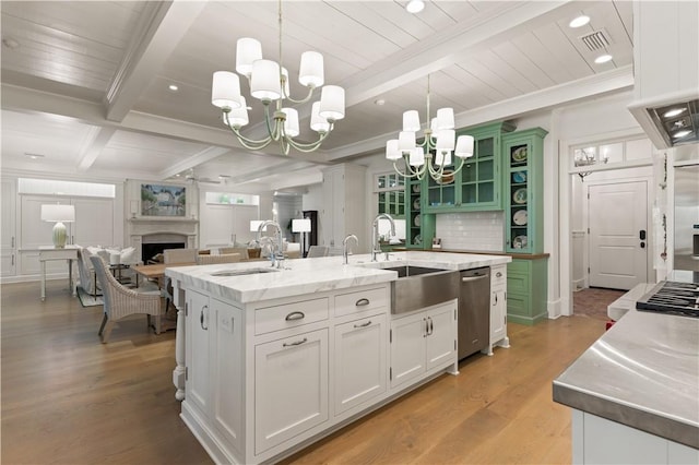 kitchen featuring sink, light hardwood / wood-style flooring, decorative light fixtures, a kitchen island with sink, and white cabinets