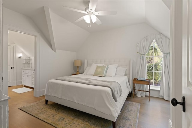 bedroom featuring wood-type flooring, connected bathroom, ceiling fan, and lofted ceiling