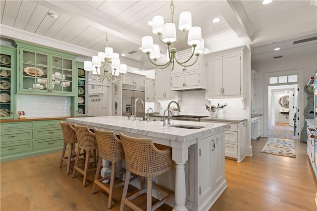 kitchen featuring light wood-type flooring, white cabinetry, and an island with sink