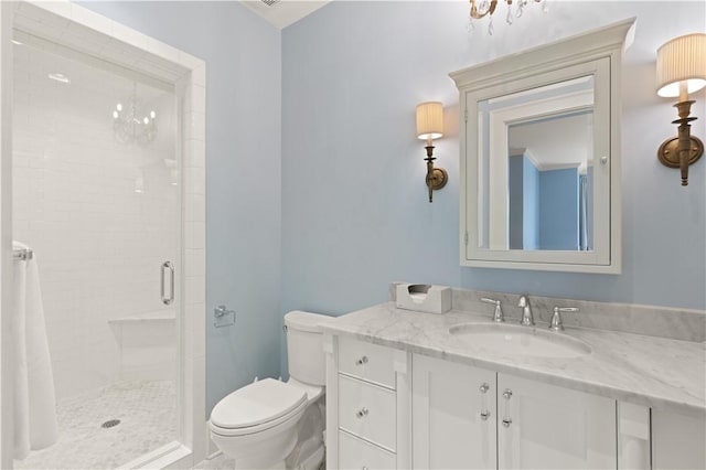 bathroom featuring a notable chandelier, vanity, toilet, and walk in shower