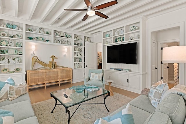 living room with built in shelves, ceiling fan, beam ceiling, light hardwood / wood-style flooring, and a fireplace