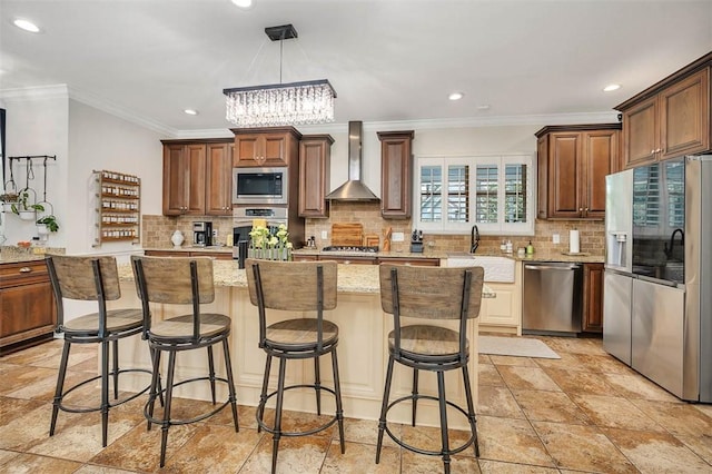 kitchen with decorative light fixtures, a center island, stainless steel appliances, and wall chimney range hood