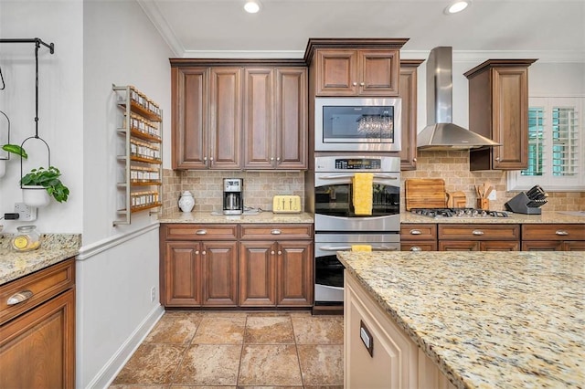 kitchen featuring backsplash, wall chimney exhaust hood, light stone countertops, ornamental molding, and appliances with stainless steel finishes