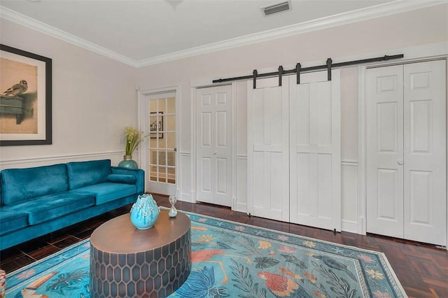 living room with dark parquet floors, a barn door, and ornamental molding