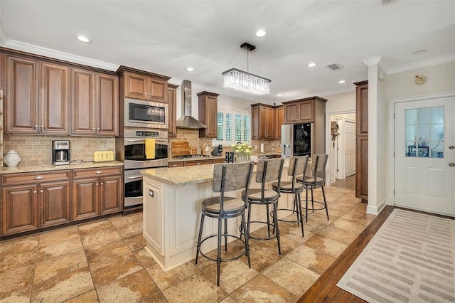 kitchen with pendant lighting, a center island, wall chimney exhaust hood, tasteful backsplash, and stainless steel appliances