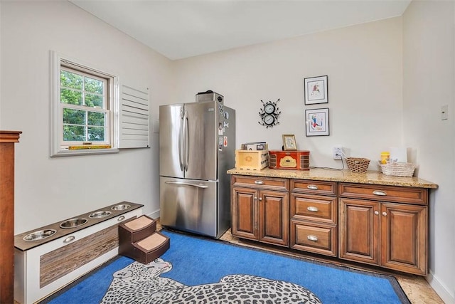 kitchen featuring light stone countertops and stainless steel refrigerator