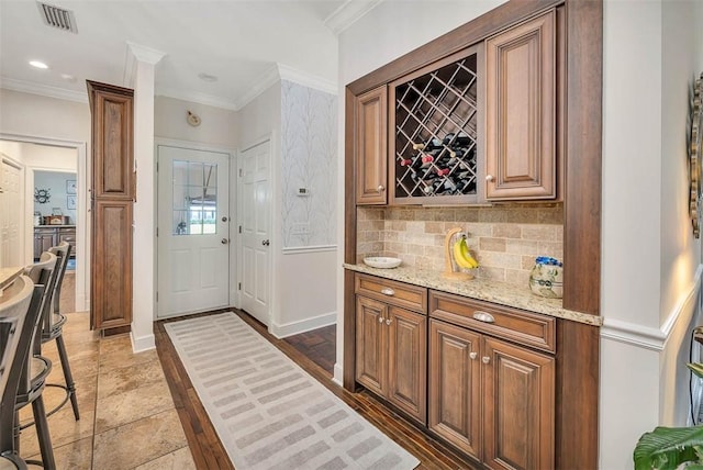 bar with backsplash, light stone counters, and crown molding