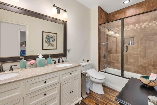 full bathroom featuring hardwood / wood-style floors, vanity, toilet, and bath / shower combo with glass door