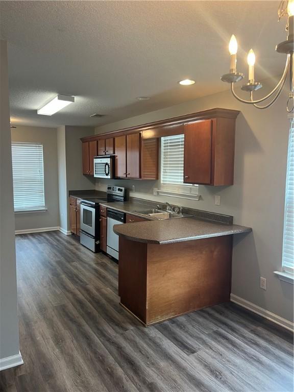 kitchen featuring dark wood-type flooring, sink, a textured ceiling, appliances with stainless steel finishes, and kitchen peninsula