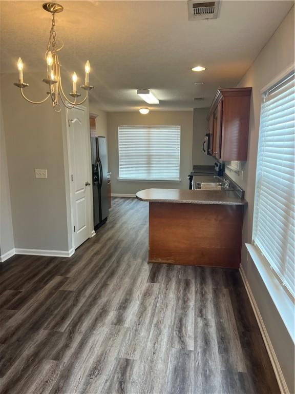 kitchen with pendant lighting, dark wood-type flooring, stainless steel appliances, and kitchen peninsula