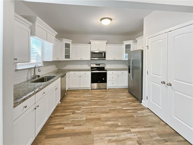 kitchen with sink, white cabinets, backsplash, stainless steel appliances, and light stone countertops