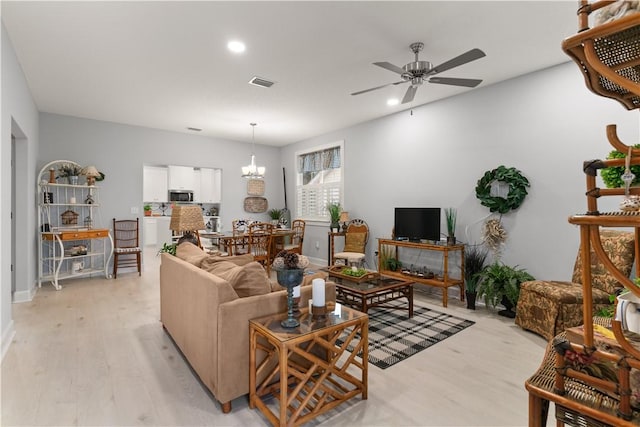 living room with light hardwood / wood-style flooring and ceiling fan with notable chandelier