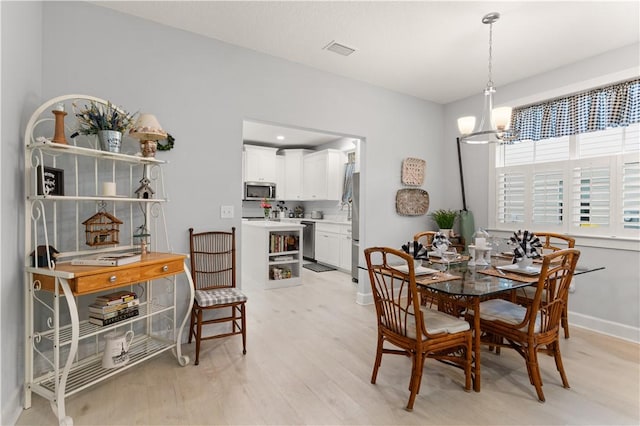 dining area featuring a notable chandelier and light wood-type flooring