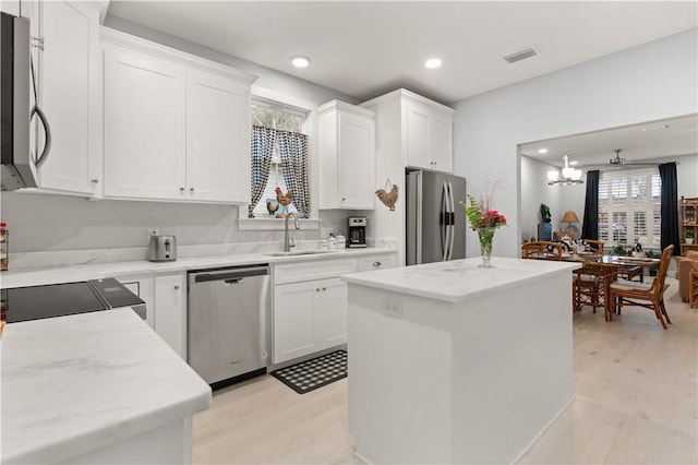 kitchen featuring white cabinetry, sink, light hardwood / wood-style floors, a kitchen island, and appliances with stainless steel finishes