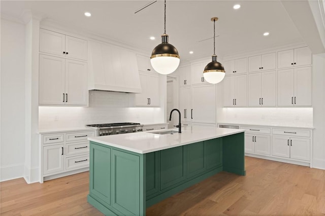 kitchen featuring premium range hood, range, sink, and white cabinets