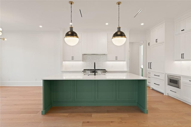 kitchen featuring a kitchen island with sink, hanging light fixtures, white cabinetry, and tasteful backsplash