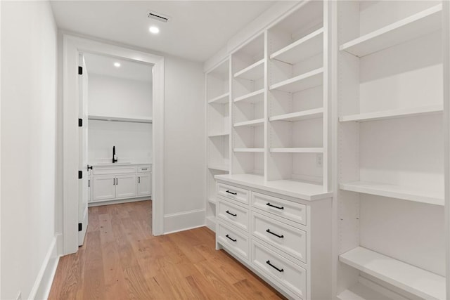 walk in closet featuring sink and light hardwood / wood-style flooring