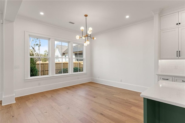 unfurnished dining area featuring ornamental molding, a chandelier, and light hardwood / wood-style flooring