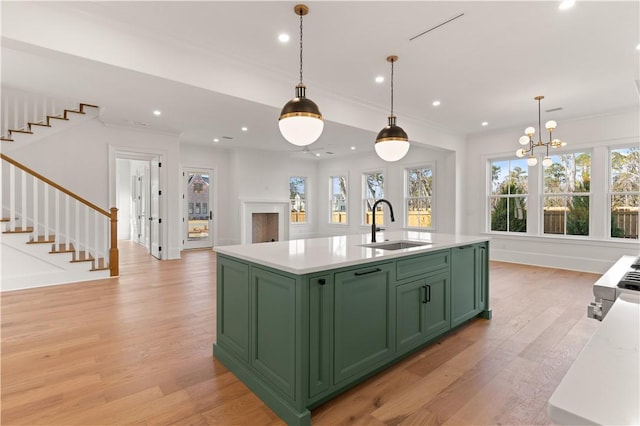 kitchen featuring pendant lighting, a kitchen island with sink, sink, and light wood-type flooring