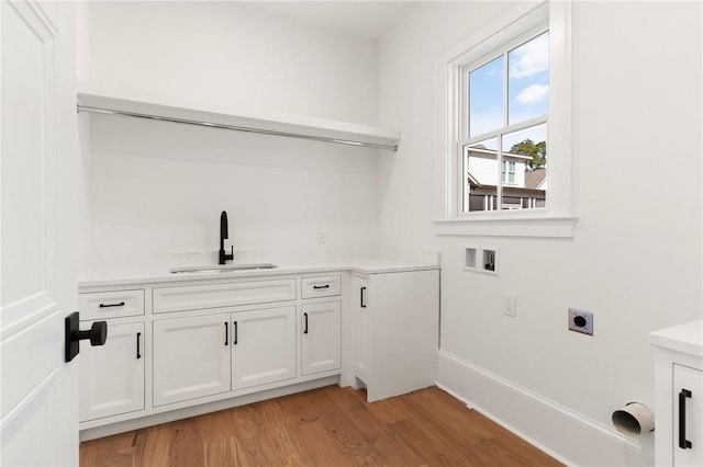 laundry area with sink, electric dryer hookup, cabinets, washer hookup, and light wood-type flooring