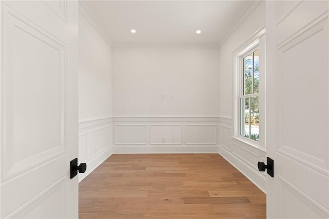 spare room with ornamental molding and light wood-type flooring