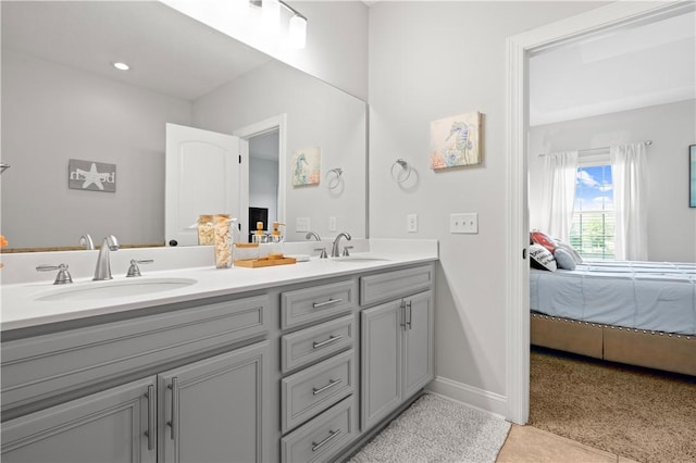 ensuite bathroom with double vanity, a sink, baseboards, and ensuite bath