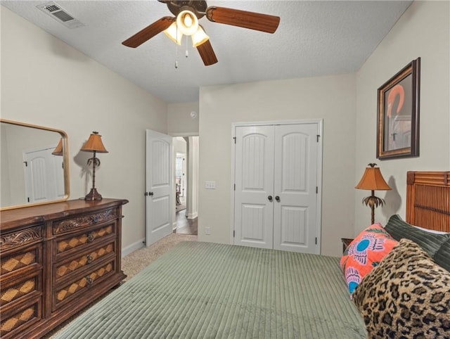 carpeted bedroom with a textured ceiling, a closet, and ceiling fan