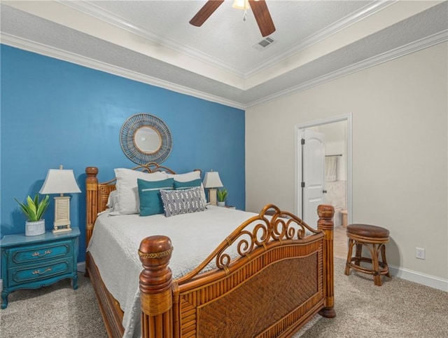 carpeted bedroom featuring ceiling fan, a raised ceiling, ornamental molding, and ensuite bath