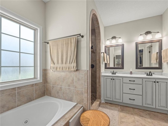 bathroom with vanity, a healthy amount of sunlight, a textured ceiling, and independent shower and bath