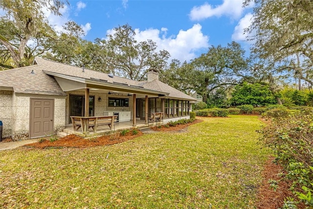 217 Five Pounds Rd, Saint Simons Island, GA 31522 - back of property featuring a chimney, a lawn, a patio, and roof with shingles