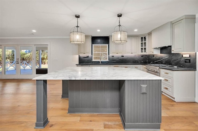 111 Youngwood Dr, Saint Simons Island, GA 31522 - kitchen with high end stove, decorative backsplash, light stone counters, light wood-style floors, and a kitchen bar