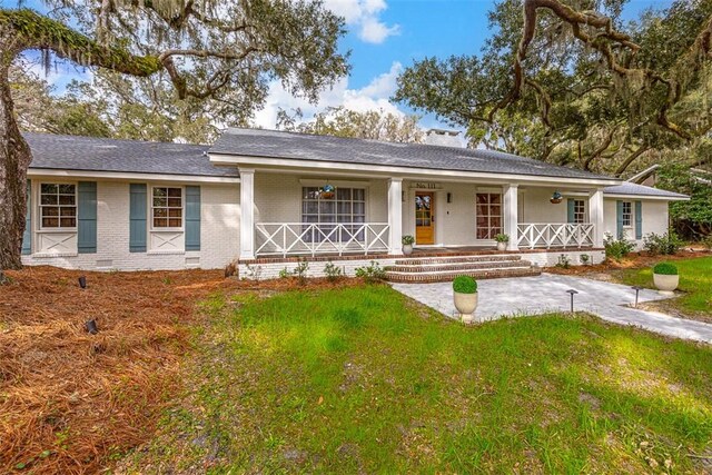 111 Youngwood Dr, Saint Simons Island, GA 31522 - ranch-style house featuring covered porch, brick siding, a front yard, crawl space, and a shingled roof