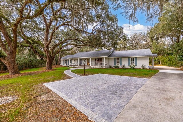 111 Youngwood Dr, Saint Simons Island, GA 31522 - ranch-style home with a porch, a front lawn, and driveway