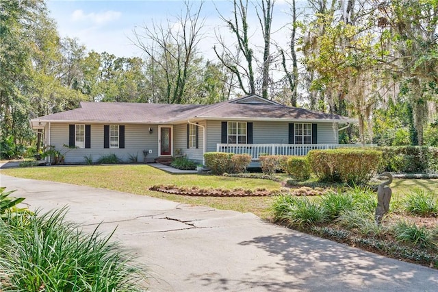 ranch-style house featuring covered porch and a front lawn