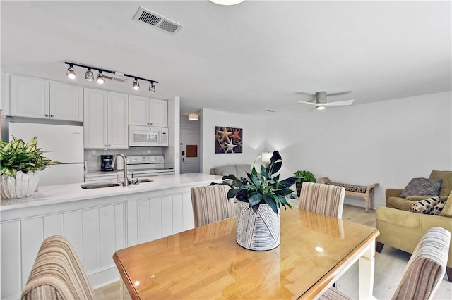 dining space featuring ceiling fan, sink, and light wood-type flooring