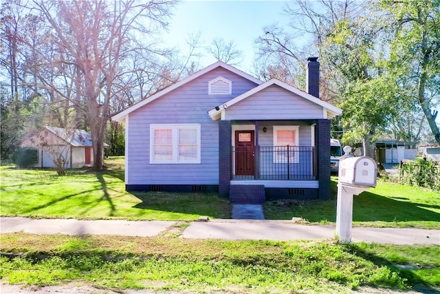 bungalow-style home featuring a porch, a front yard, and a chimney