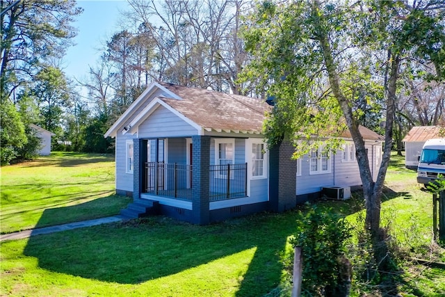 back of property with roof with shingles, crawl space, cooling unit, a yard, and brick siding