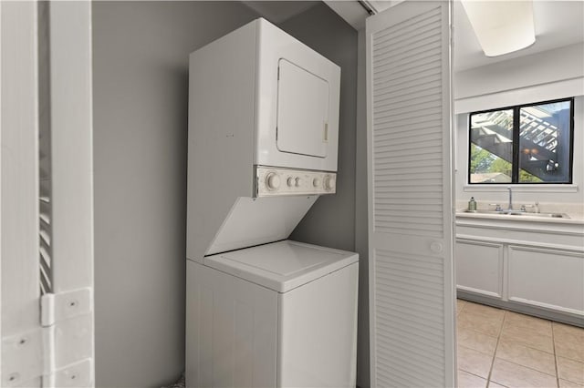 washroom featuring stacked washer / dryer, sink, and light tile patterned flooring