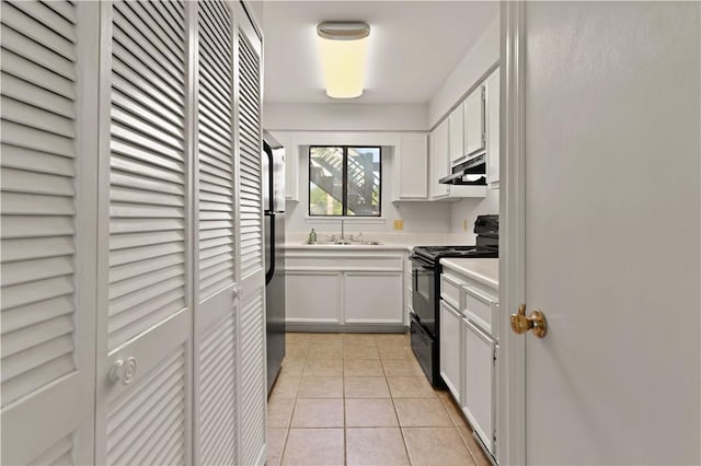 kitchen featuring white cabinets, sink, electric range, stainless steel fridge, and light tile patterned floors