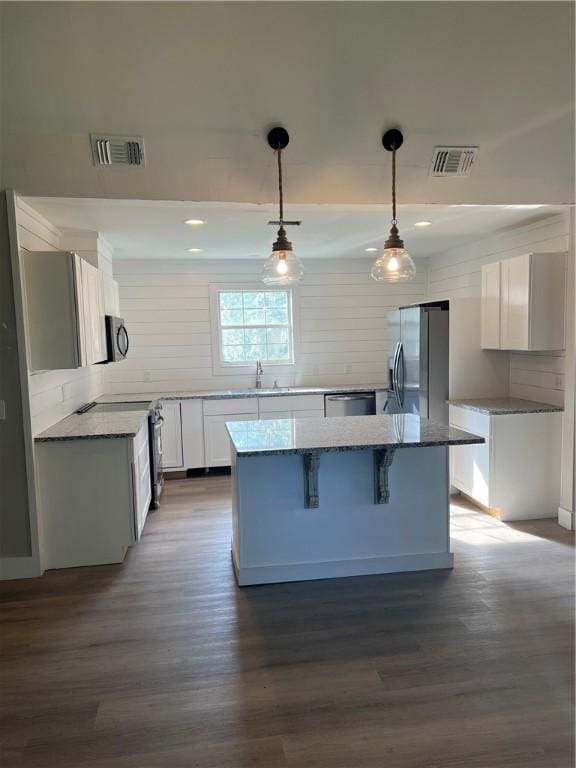 kitchen featuring visible vents, decorative backsplash, a kitchen island, dark wood-style flooring, and stainless steel appliances