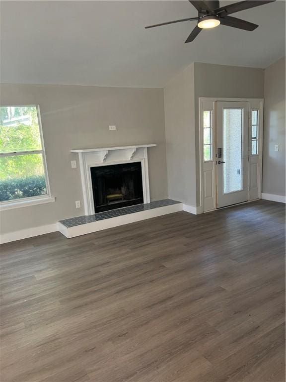 unfurnished living room with ceiling fan, a fireplace, baseboards, and wood finished floors