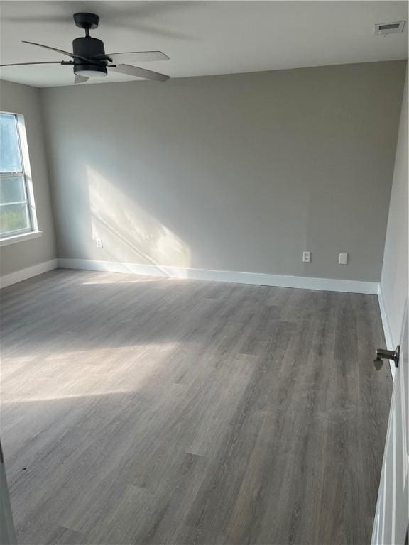 unfurnished room with ceiling fan, wood finished floors, visible vents, and baseboards