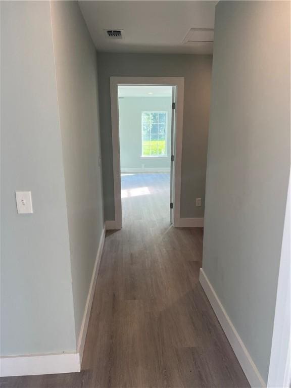 hall featuring visible vents, baseboards, and wood finished floors